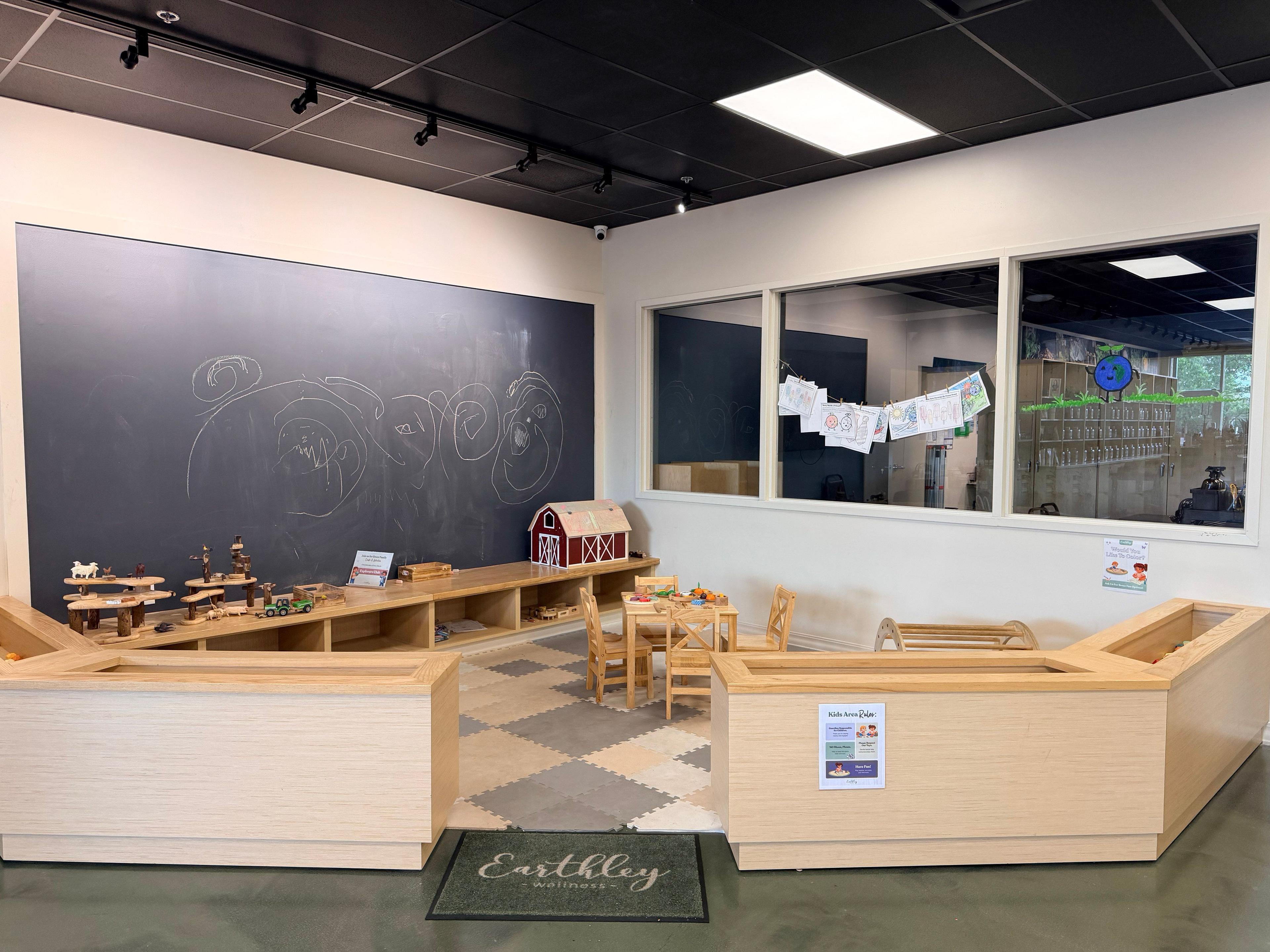 Earthley Wellness store kids' play area with chalkboard wall and wooden toys