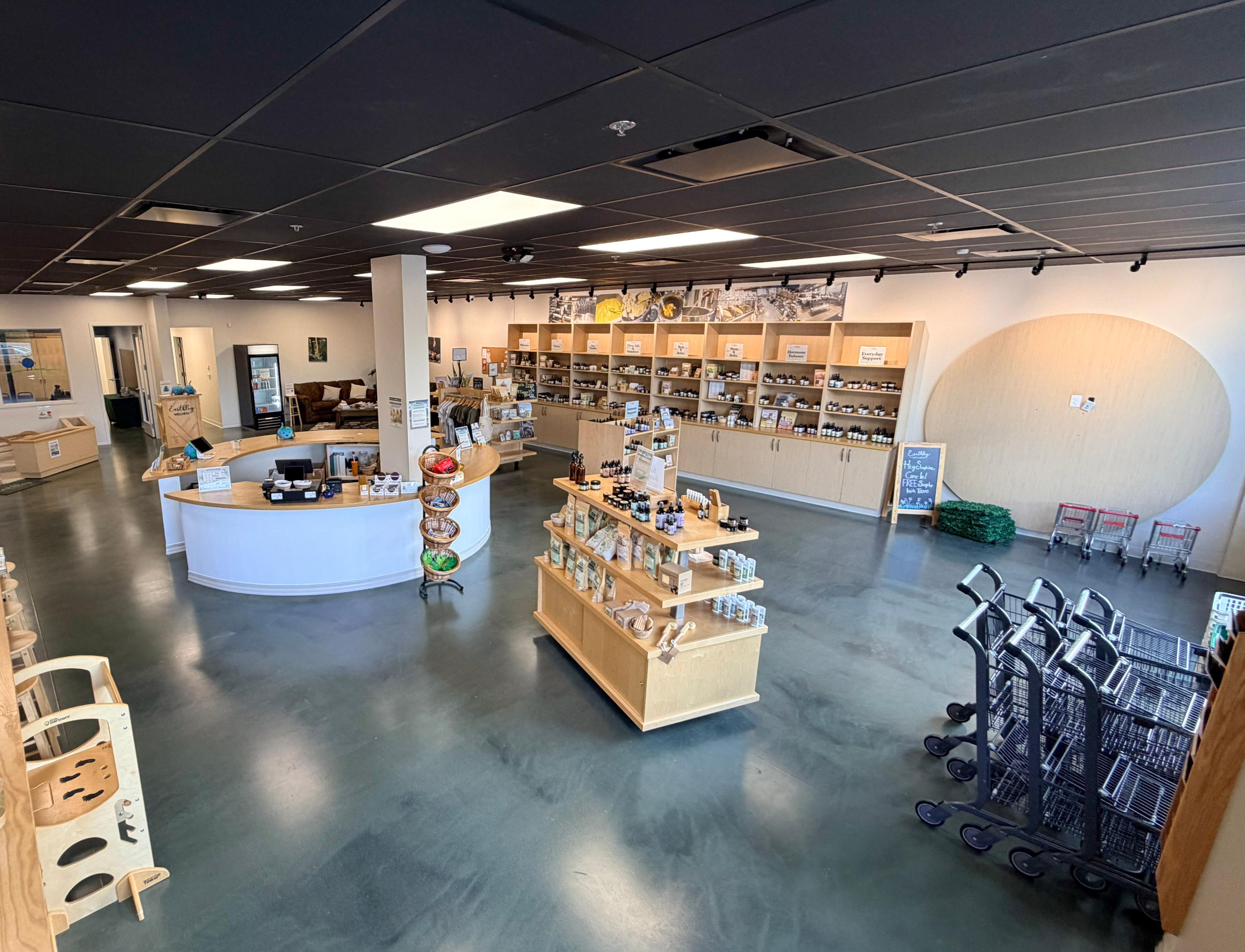 Earthley Wellness retail store interior with wood shelving, herbal products, and curved checkout counter.