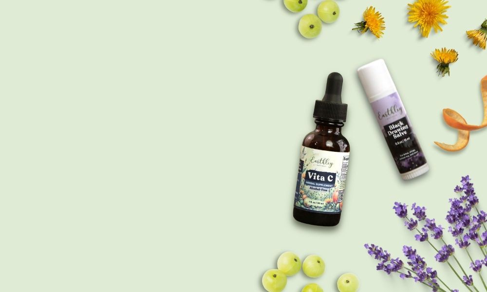 Earthley Vita C tincture and Nourish Serum surrounded by dandelions, lavender, and green berries on sage background