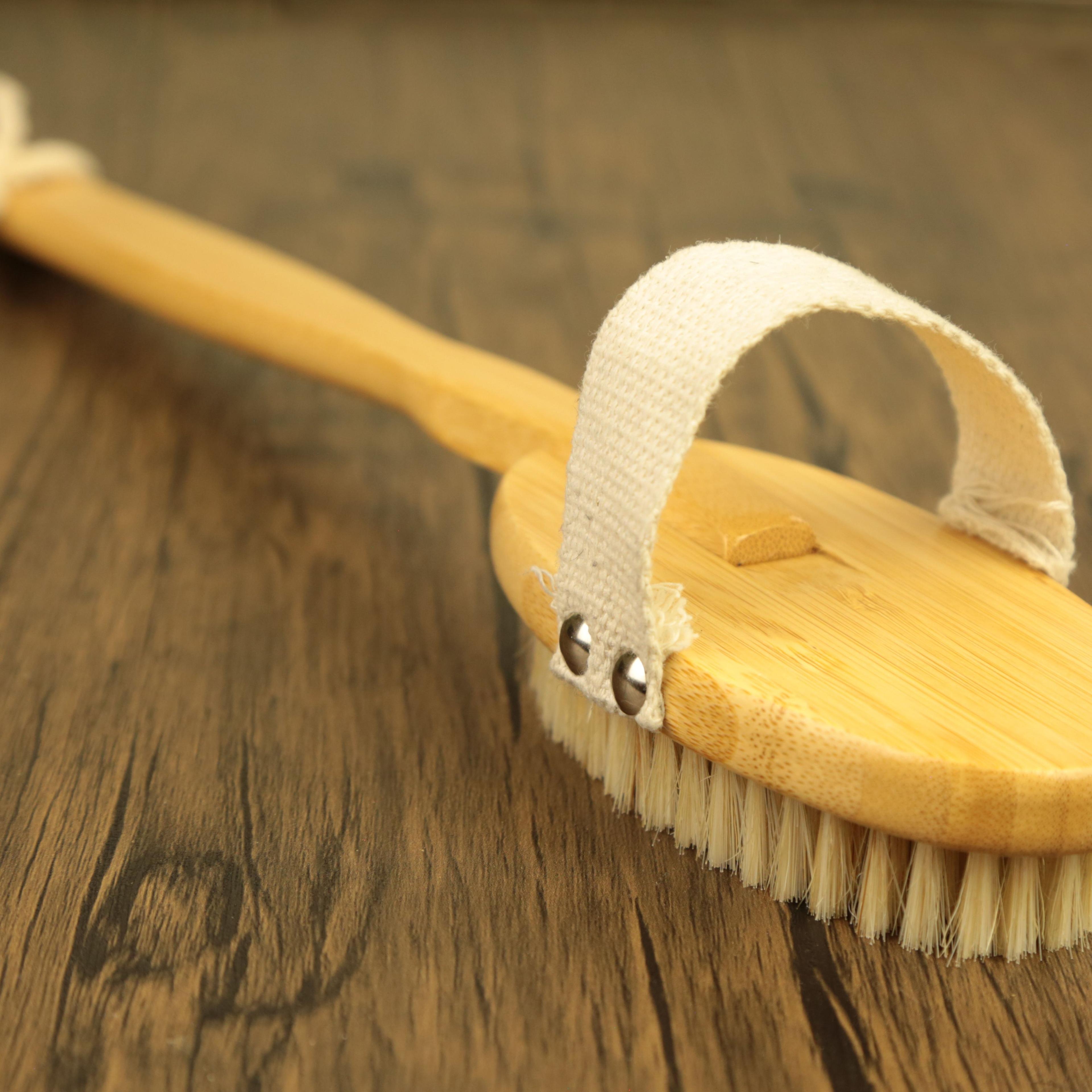Natural bamboo dry brush with cotton strap and natural bristles on wooden surface for body exfoliation