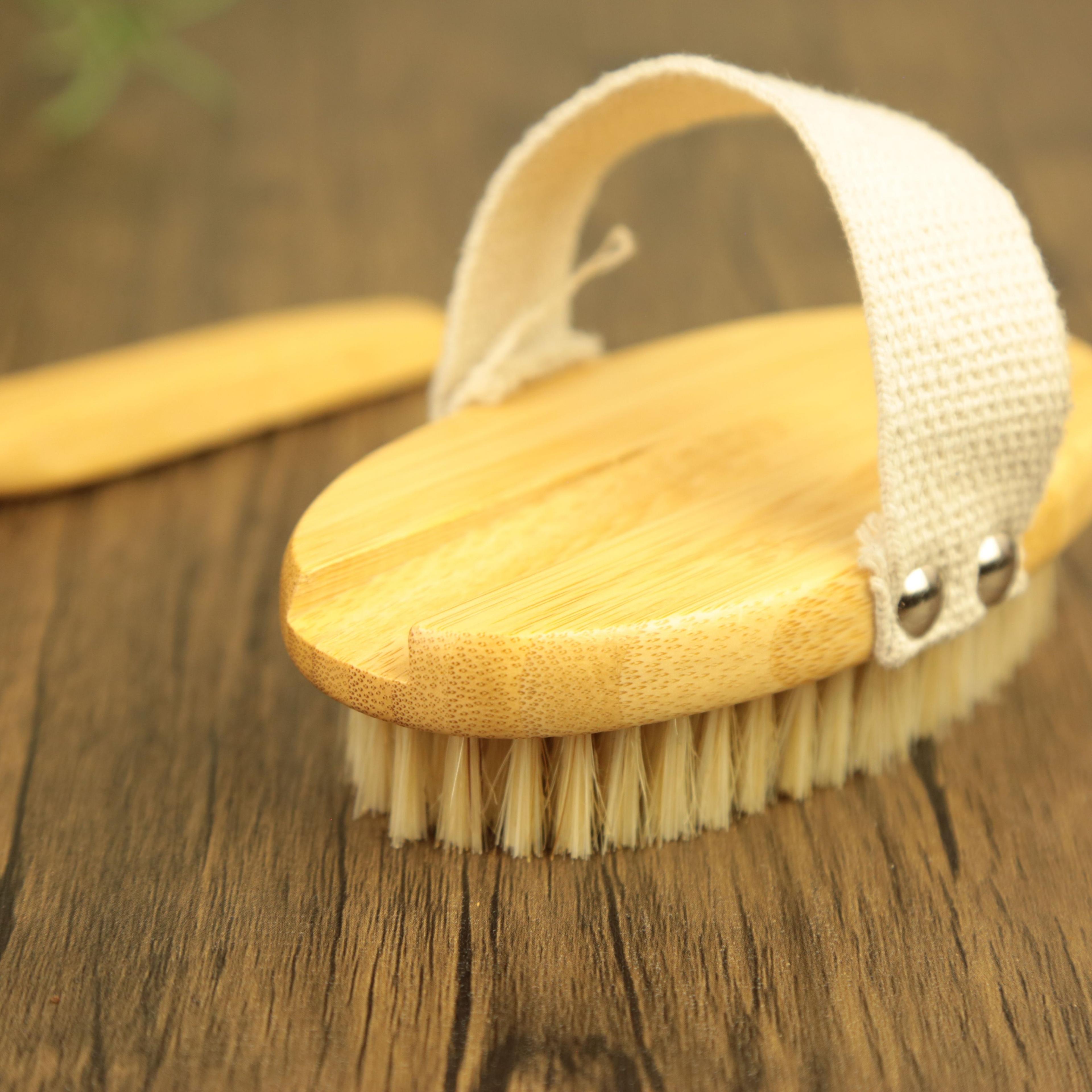 Natural bamboo dry brush with white cotton strap and soft bristles on wooden surface for body exfoliation