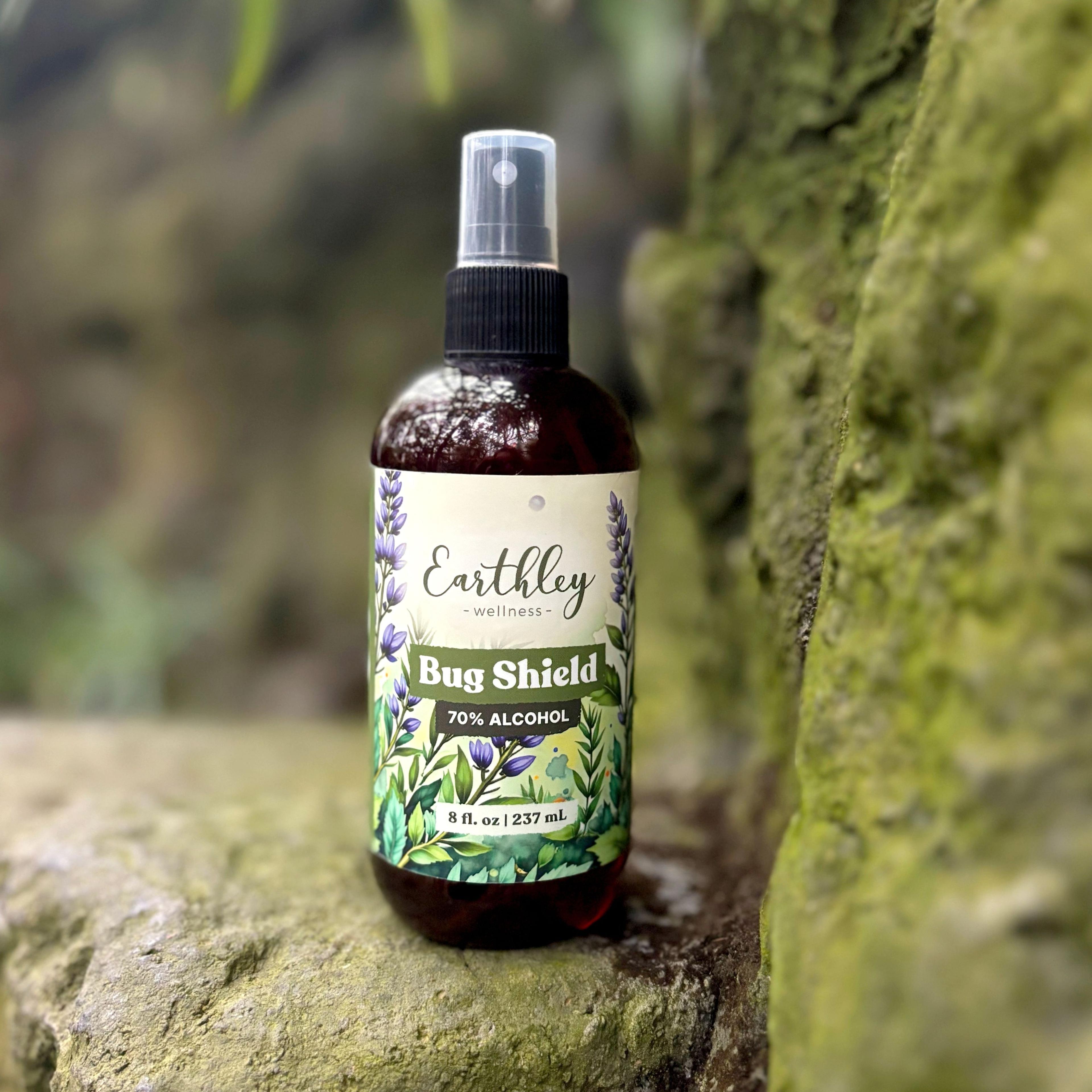 Earthley Bug Shield spray bottle with botanical label design sitting on moss-covered tree bark in natural outdoor setting