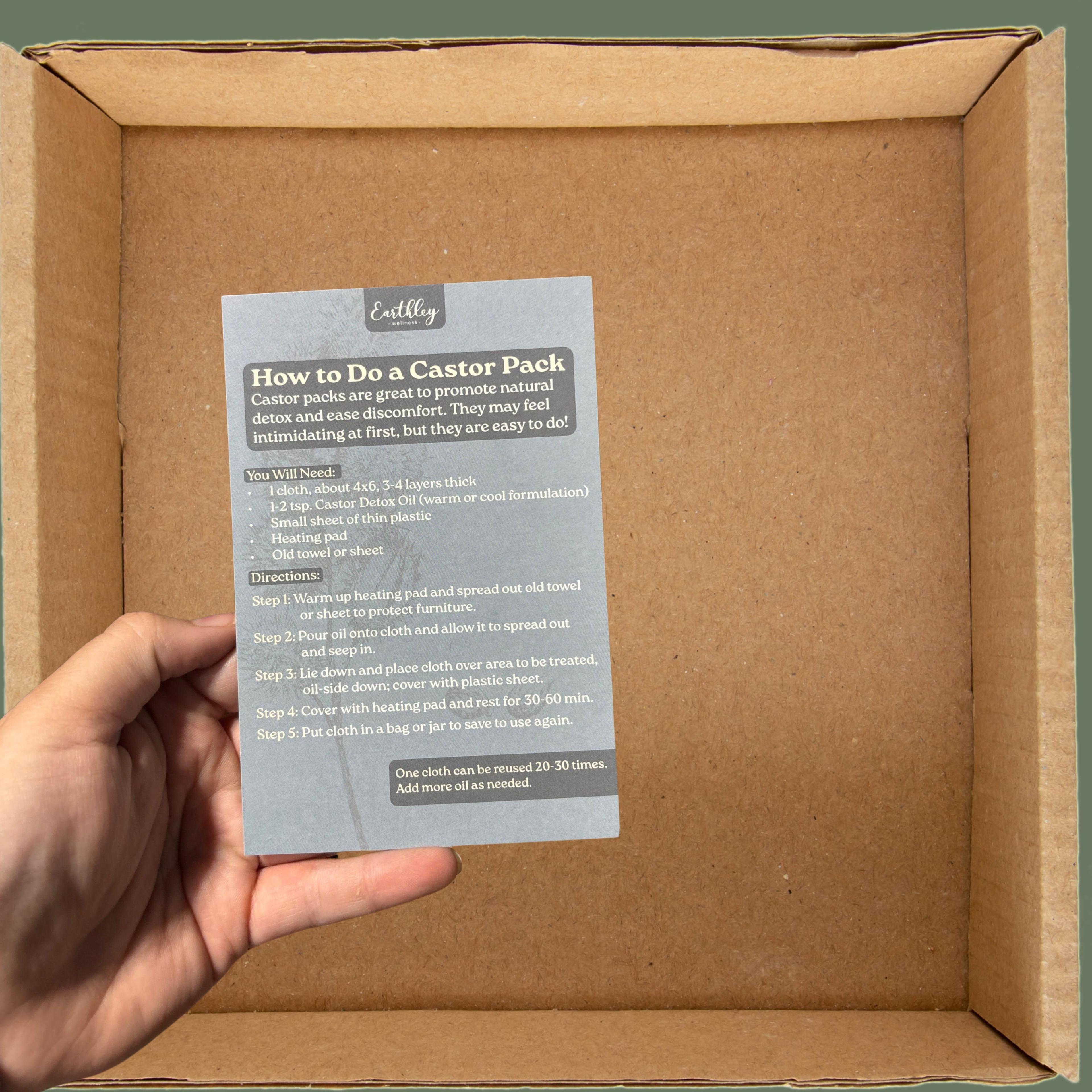 Hand holding Earthley instruction card for castor pack application inside cardboard shipping box