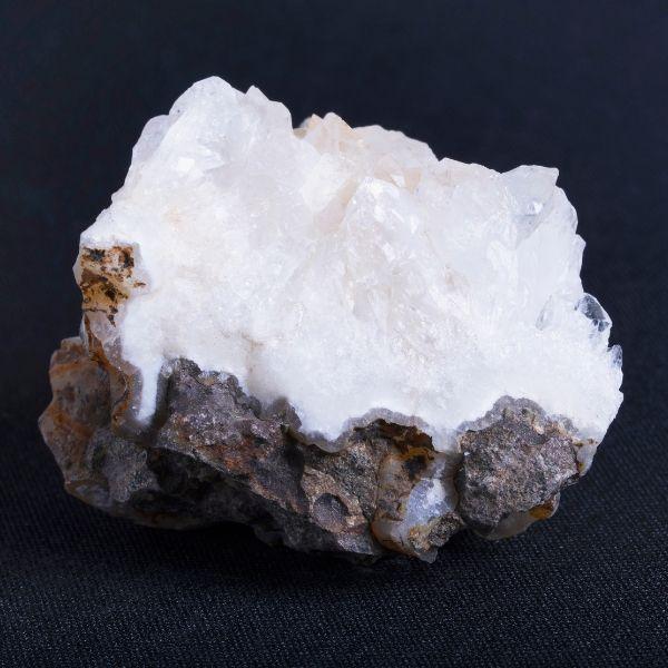 Raw white quartz crystal cluster on dark rocky matrix base