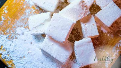 White herbal soap bars cut into squares on wooden surface dusted with powder