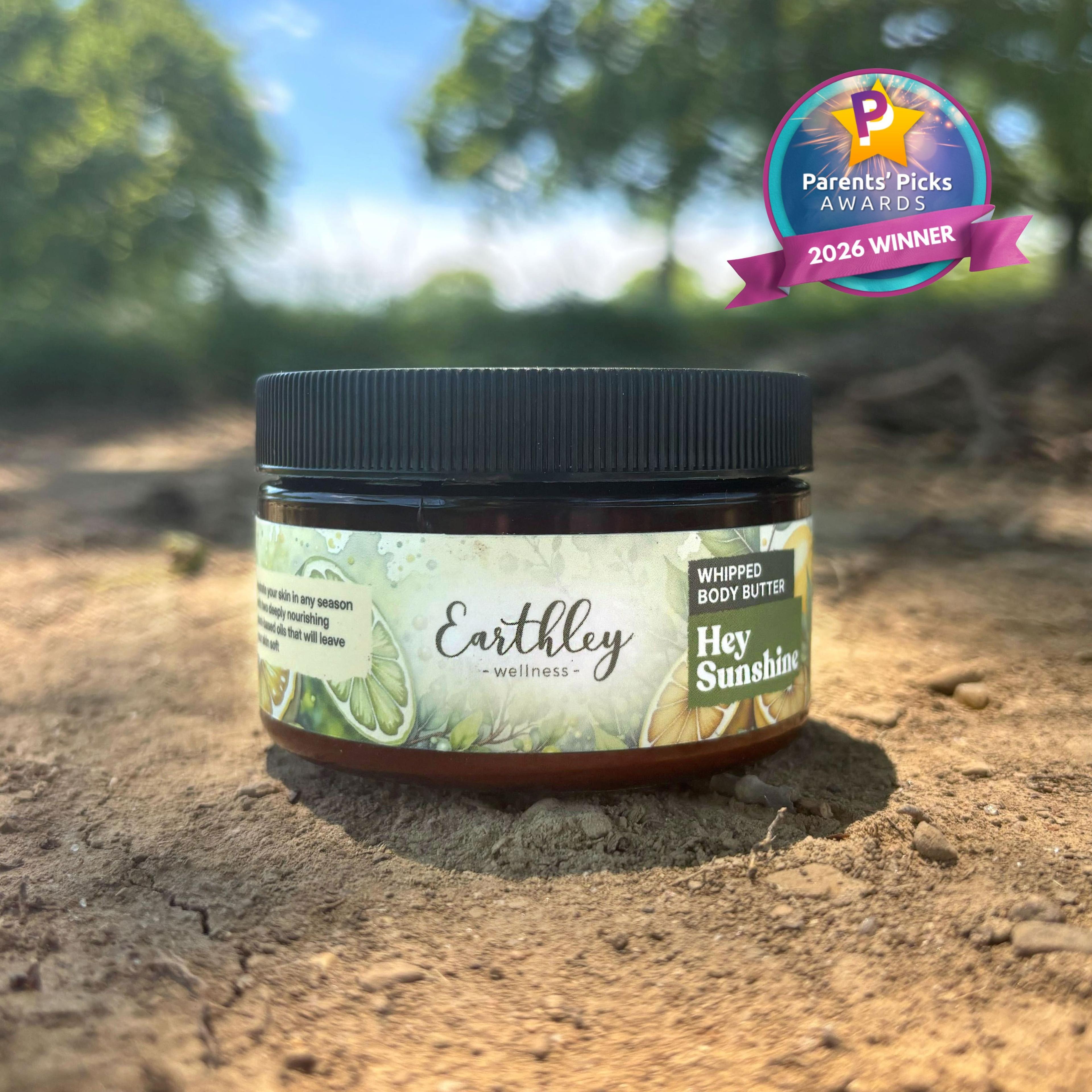 Earthley Wellness Hey Sunshine whipped body butter jar on natural ground with Parents' Picks Awards 2026 Winner badge