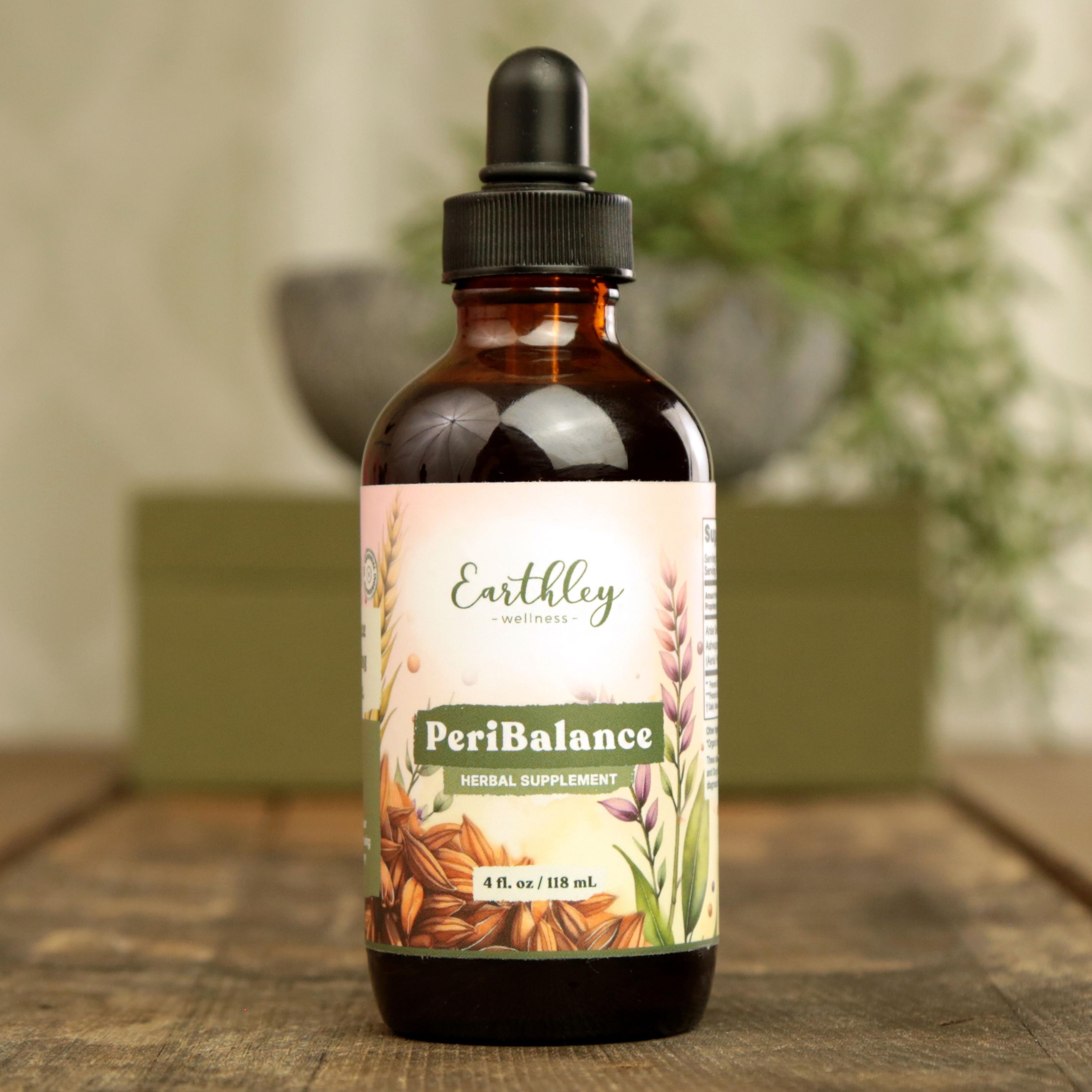 Earthley PeriBalance 4 oz amber dropper bottle with soft pink botanical label featuring oats, wheat, and lavender, labeled as Herbal Supplement, on wooden surface with mortar and greenery in background