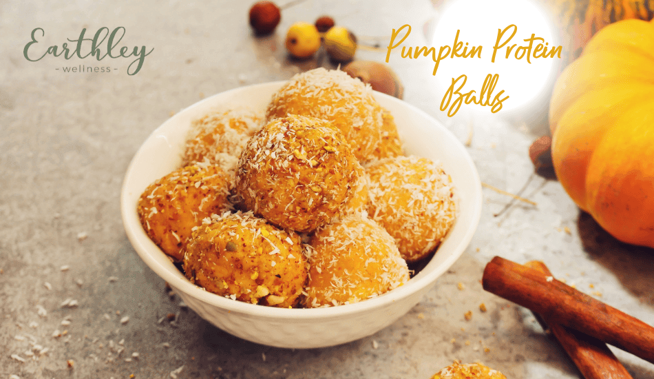 Pumpkin Protein Balls recipe header showing white bowl filled with golden orange coconut-coated energy balls with small pumpkin cinnamon sticks and scattered coconut on gray surface