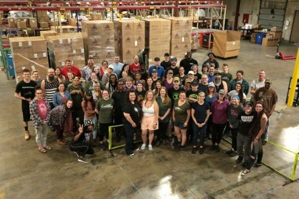Earthley full team of approximately 50 employees gathered in warehouse with shipping boxes