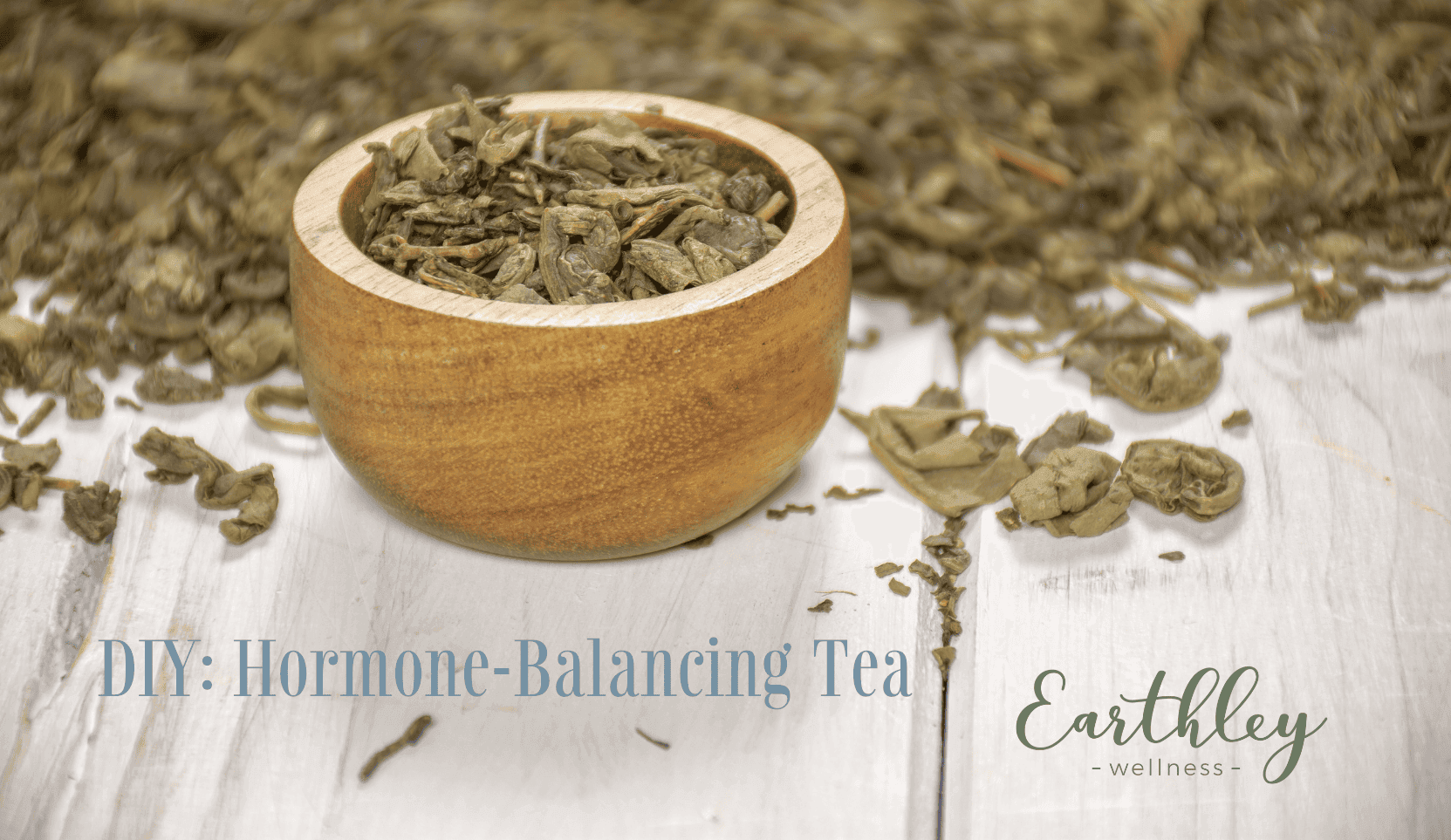 DIY Hormone-Balancing Tea recipe header showing wooden bowl filled with dried green tea leaves on rustic wood surface with scattered loose leaf tea