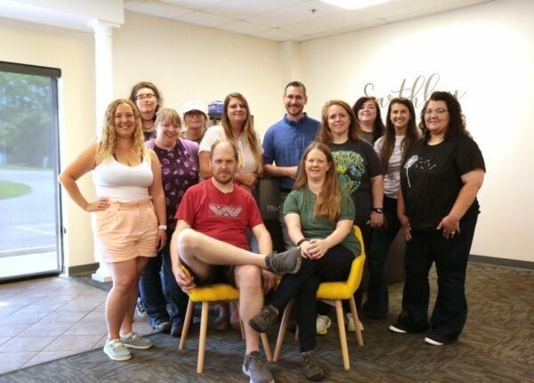 Earthley Leadership Team group photo showing employees smiling together in office setting with natural lighting and cream background