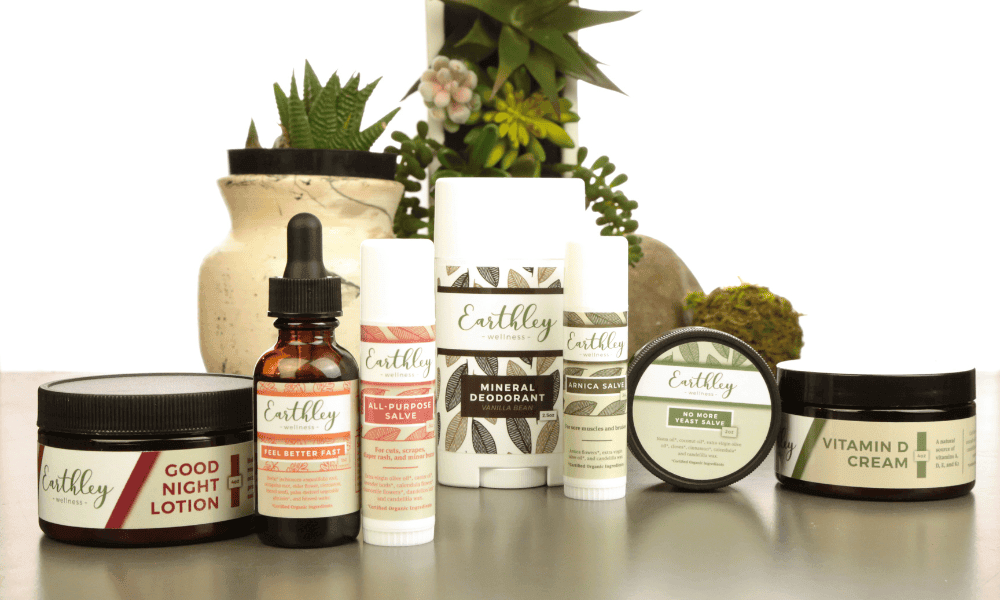 Collection of Earthley wellness products including Good Night Lotion tinctures and creams arranged with houseplants