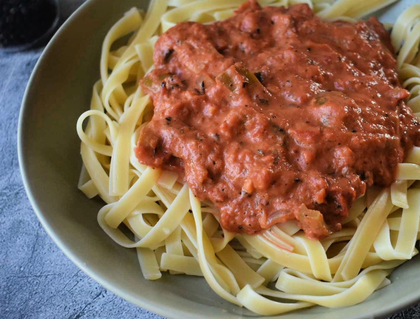Bowl of fettuccine pasta topped with chunky red tomato sauce with herbs and spices